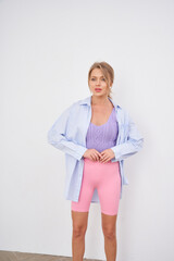 Woman in a pastel outfit stands confidently; light blue shirt over a lavender top and pink shorts....