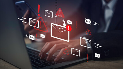 Hands using laptop and phone with spam email warning icons, representing phishing, cybersecurity threats, email scams, and data protection alerts.