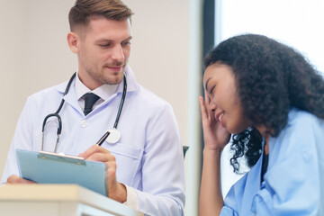 doctor in white gown with stethoscope,asking a woman patient on wheelchair a present illness and writing paper on clipboard to diagnosis and treatment