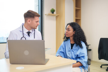 doctor in white gown with stethoscope,asking a woman patient on wheelchair a present illness and writing paper on clipboard to diagnosis and treatment