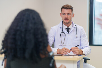 doctor in white gown with stethoscope,asking a woman disabled person on wheelchair for present illness to diagnosis and treatment in the examine room