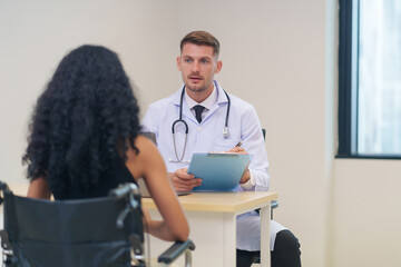 doctor in white gown with stethoscope,asking a woman disabled person on wheelchair for present illness to diagnosis and treatment in the examine room