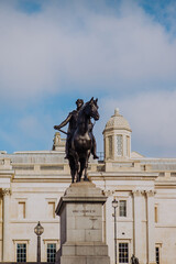 Obraz premium The iconic National Gallery stands prominently in London's Trafalgar Square, its grand Neoclassical façade a beacon for art and history in the heart of the city.