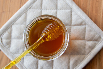 Glass bowl of natural honey and yellow spoon on the table.