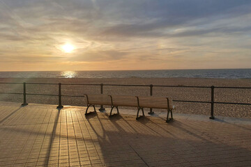 Empty bench on the beach. Alone by the sea at sunset. © Iryna