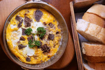 Savory egg and meat dish with fresh bread for breakfast