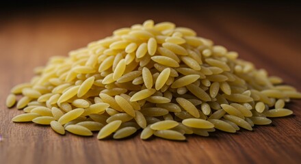 Obraz premium Risoni Pasta Pile on Wood - A mound of pale yellow risoni pasta rests on a dark brown wooden surface. This symbolizes cooking, Italian cuisine, food ingredients, healthy eating, and culinary arts