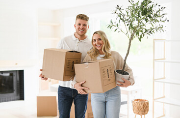 Young couple moving in new home. Couple is having fun with cardboard boxes in new house at moving...