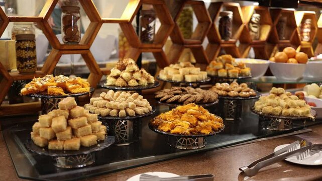Traditional Middle Eastern desserts sweet buffet baklava maamoul konafa honey pastries arranged on elegant trays inviting textures golden crispy layers nutty filling cozy luxurious vibe