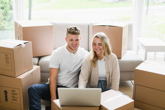 Young couple moving in new home. Couple is having fun with cardboard boxes in new house at moving day.