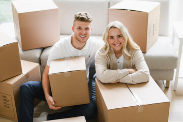 Young couple moving in new home. Couple is having fun with cardboard boxes in new house at moving day.