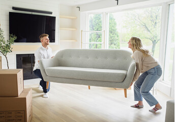 Young couple moving in new home. Couple is having fun with cardboard boxes in new house at moving...