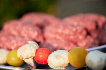 Vegetables and pieces of minced meat are being cooked on a BBQ