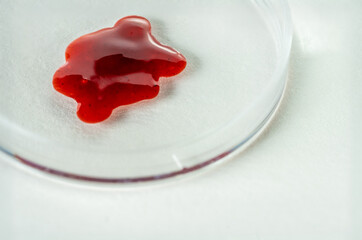 Red blood sample in petri dish on white background as macro shot