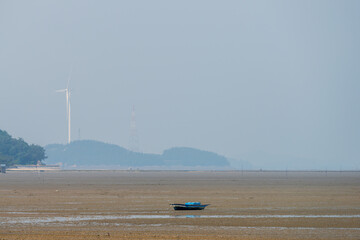 Old Fishing Boat on Tidal Flat with Wind Turbine