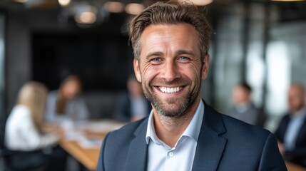 Obraz premium Confident businessman smiling in a modern office with colleagues in the background.