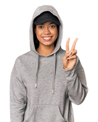 Young Filipino woman in studio showing victory sign and smiling broadly.