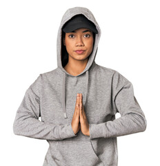 Young Filipino woman in studio praying, showing devotion, religious person looking for divine inspiration.