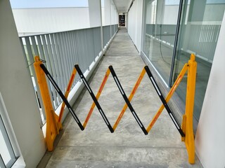 A bright yellow and dark black barrier is in the center of a hallway