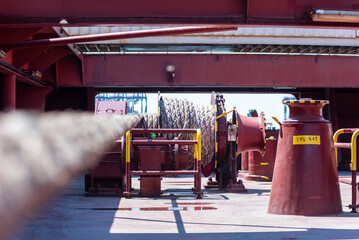 Large mooring winch on a ship's deck, featuring thick, braided ropes wound around a cylindrical metal drum. 