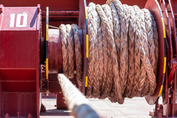Large mooring winch on a ship's deck, featuring thick, braided ropes wound around a cylindrical metal drum. 