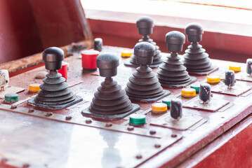 Control console with switches and joysticks used to operate the mooring winches on a commercial cargo ship.
