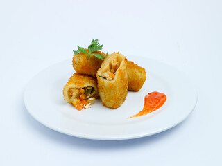 Crispy vegetable risol cut open on a white plate, served with chili sauce. isolated on white background