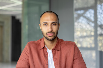 A portrait of a young man with a short haircut and a red shirt, looking directly at the camera.