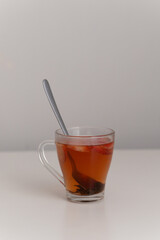 Strawberry tea with fruit slices in a glass mug and spoon