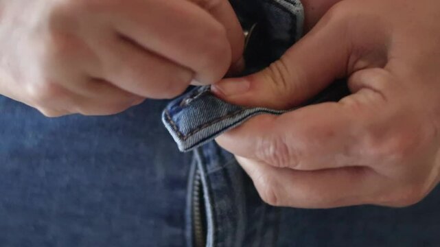 Un primer plano  de una mujer blanca mayor de 50 a&ntilde;os tratando de abrocharse el pantal&oacute;n con dificultad por el sobrepeso, presenta exceso de grasa abdominal  