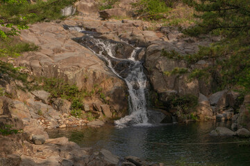 Jangsan Waterfall tranquil flow surrounded by lush forest, Busan, South Korea, nature landscape
