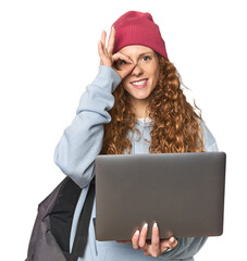 Redhead young woman student with laptop excited keeping ok gesture on eye.