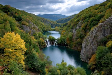 Fototapeta premium Waterfall cascades into a serene lake nestled amidst verdant treecovered hills