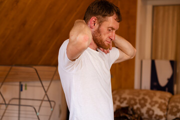 A professional sportsman in a white shirt is standing, holding his hands on his head as he performs...
