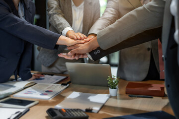 Hands joined in stack by diverse team at office meeting table showing harmony, mutual trust and...