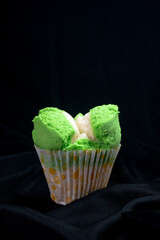 Green sweet steamed sponge cake with soft texture on black cloth with dark background, suitable for advertising or promotion.