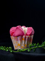 Pink blooming steamed cake in paper cup on black cloth and leaf decoration with dark background, suitable for advertising or promotion.