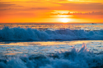 Wave on the ocean highlighted by the golden light of a sunset near the beach of La Parée in...