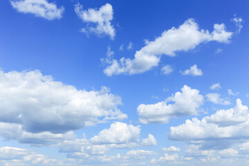 Blue cloudy sky with many beautiful white fluffy cumulus clouds in sunlight background texture