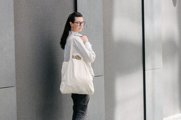 Woman walking in the city with a white tote eco bag