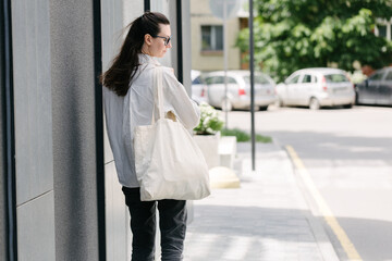 Woman walking in the city with a white tote eco bag