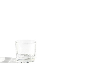 On a white background there is an empty transparent glass for vodka.	