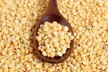  A wooden spoon with dry yellow peas lies on the surface.	