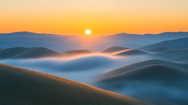 Sunrise over rolling hills shrouded in mist