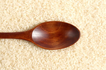 Texture rice cereal lies on a flat surface with a wooden spoon.