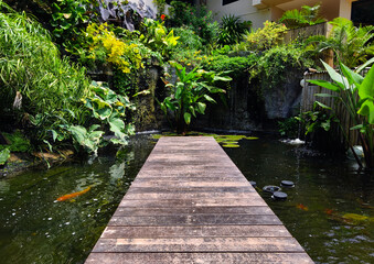 A charming wooden bridge spans a tranquil pond in a serene garden