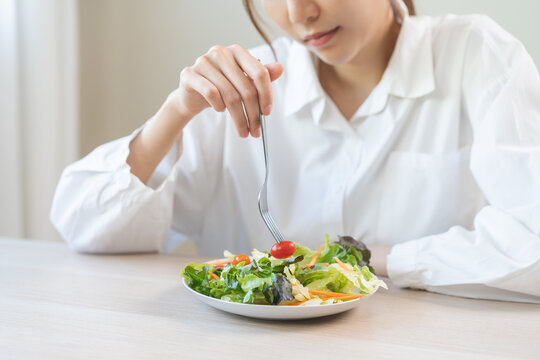 Diet in bored face, unhappy beautiful asian young woman, girl on dieting, holding fork at tomato on salad plate, dislike or tired with eat fresh vegetables. Nutrition of clean, healthy food good taste - Powered by Adobe
