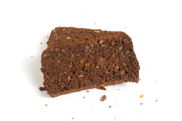 Pieces of black rye bread with sunflower seeds lie on a white background.