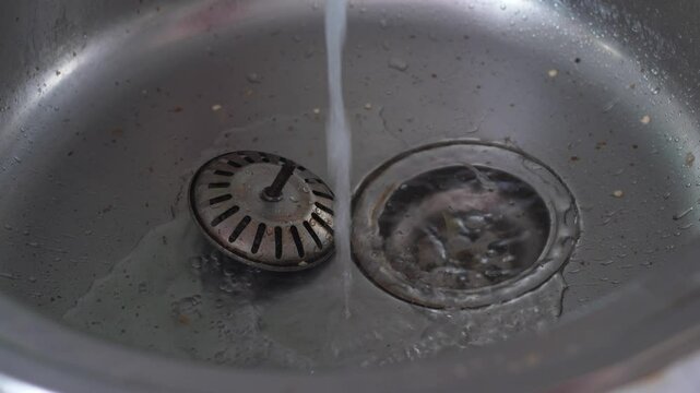 clogged kitchen sink, water flows into clogged kitchen sink with garbage and food debris, plumbing problems in the house in everyday life