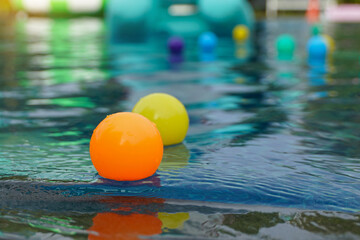 Colorful plastic balls move up and down in the same place on the surface of the water as surface waves, which are transverse waves, pass by.
